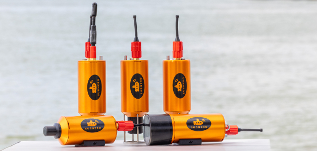 Five Subnero acoustic smart modems on a table with a harbor in the background