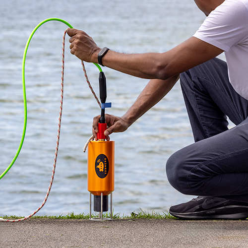 Subnero M25M Series Silver Edition acoustic smart modem being deployed by hand from a dockside during a field trial