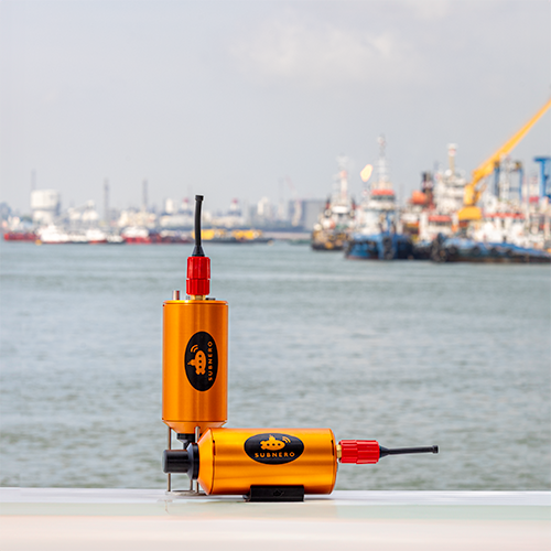 Two Subnero S40H Series Silver Edition acoustic smart modems standing on a railing with a harbor in the background, ready for high-speed underwater deployment